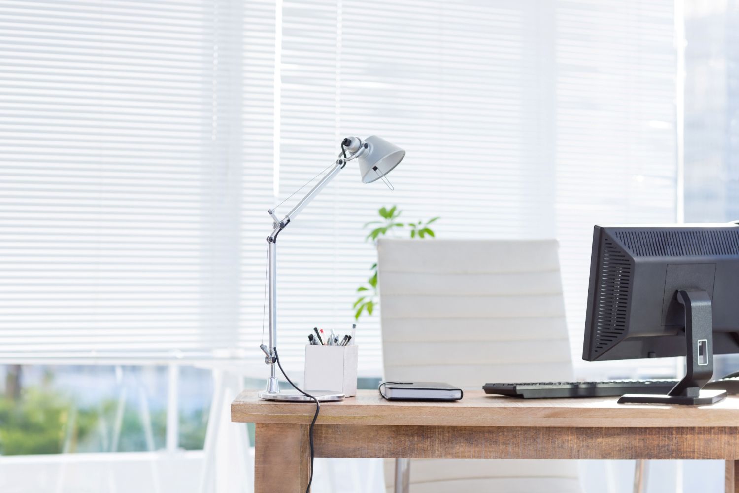 Bright home office featuring a timber desk and white Venetian blinds that filter natural light.