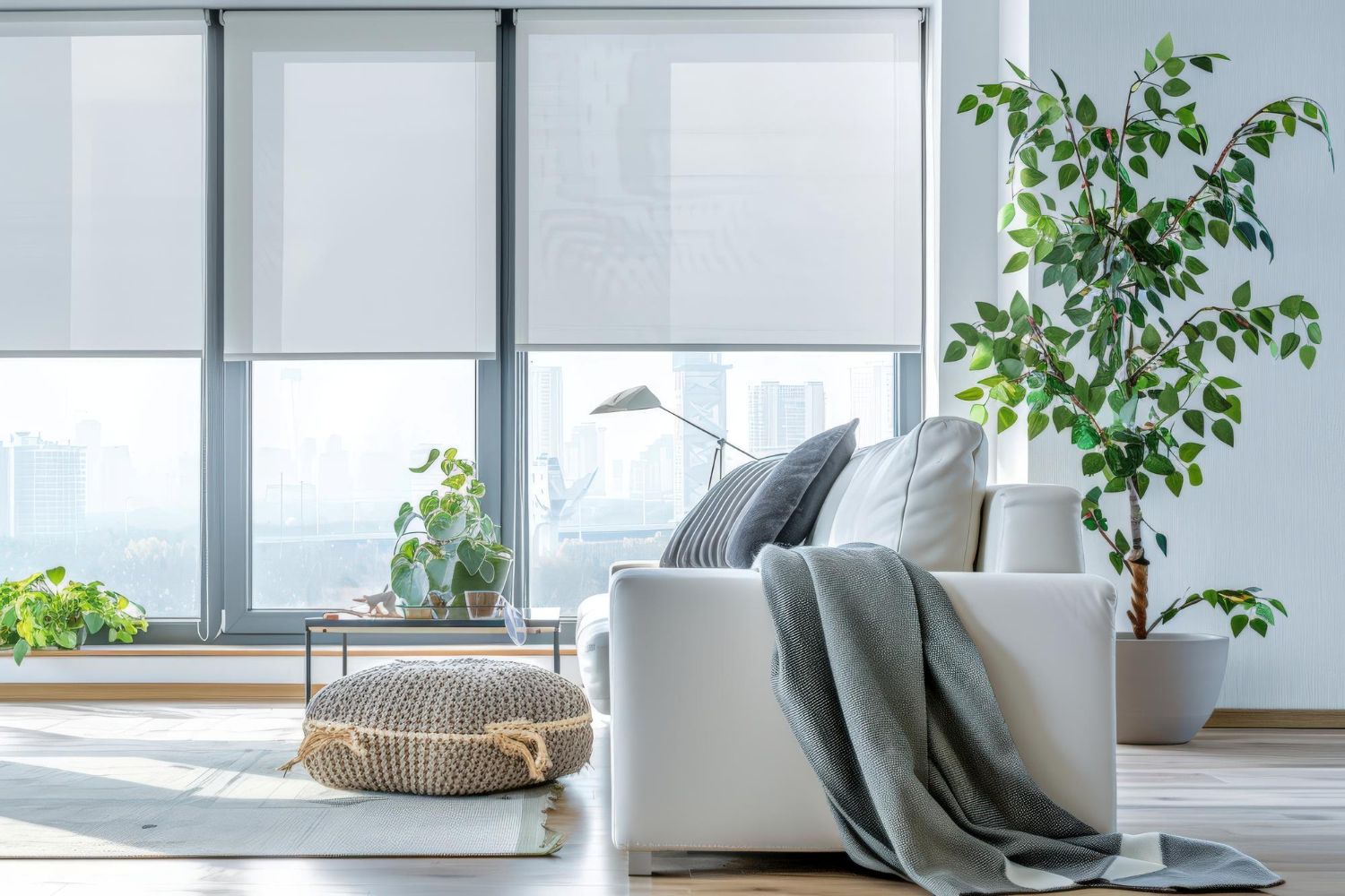 Modern apartment living room with white smart roller shades partially lowered over large floor-to-ceiling windows.